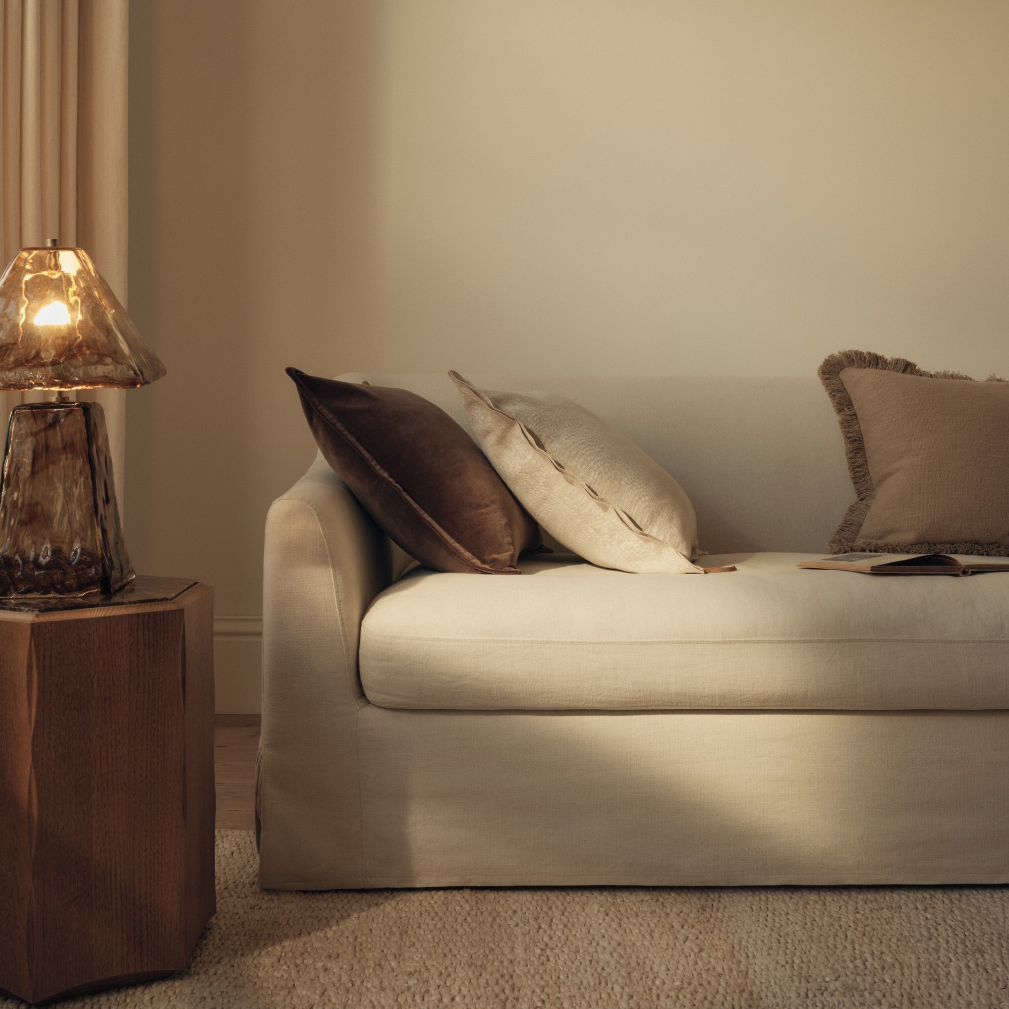 A neutral living room with a cream sofa and the M&amp;amp;S All Over Glass Table Lamp on a wooden side table