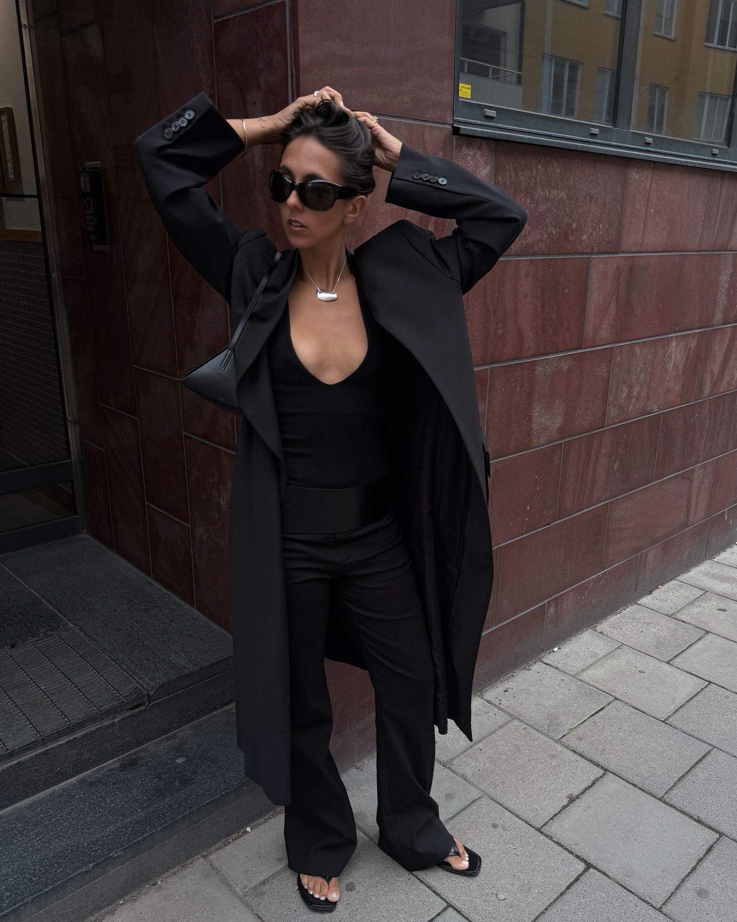 @hannamw wearing a black coat, V-neck top, and black trousers.