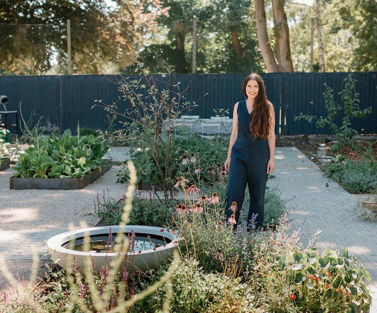 Women standing in a yard wearing a blue jumpsuit.