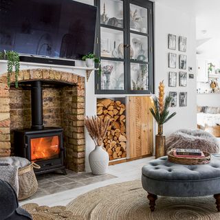living room with brick fireplace and wood burner and tv above
