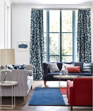 A white living room with blue and red sofas, rug and accessories.