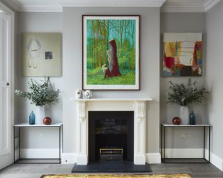 Formal living room ideas with artwork above and either side of a fireplace, with matching marble console tables