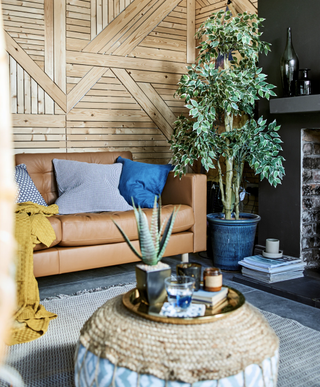 A midcentury modern living room with wooden wall decor, poof and indoor houseplant