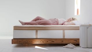 Woman in pink pajamas, lying on Saatva HD