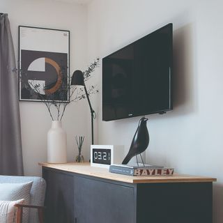 A living room with a wall-mounted TV and a TV cable hidden behind a cable duct