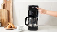 Instant Infusion Brew Coffee Maker on a countertop with a coffee cup and croissants beside it