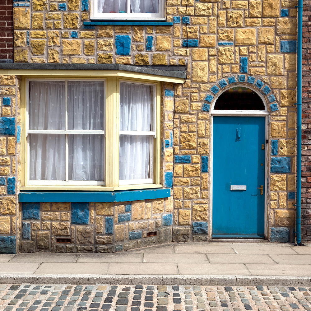 house with yellow stone wall and blue door
