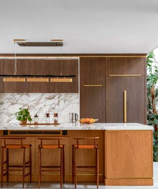 A brown wood kitchen with marble counters and backsplash