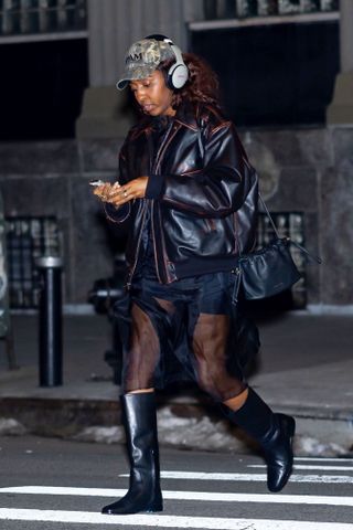 Ayo Edebiri wears a Strathberry bag and black riding boots