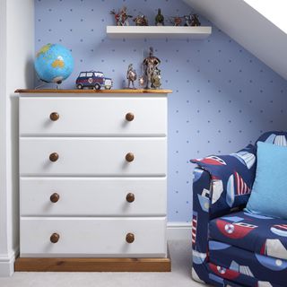 bedroom with wooden chest of drawers and patterned wallpaper