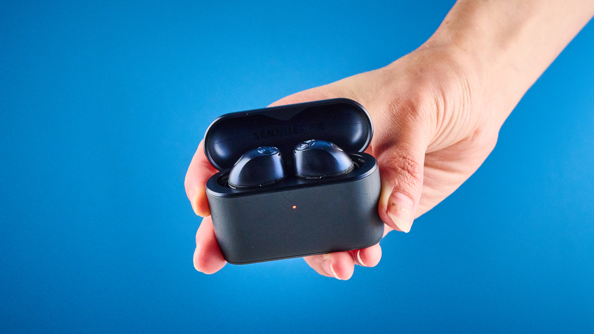 the sennheiser momentum 5 true wireless earbuds in navy photographed with the blue tom's guide background