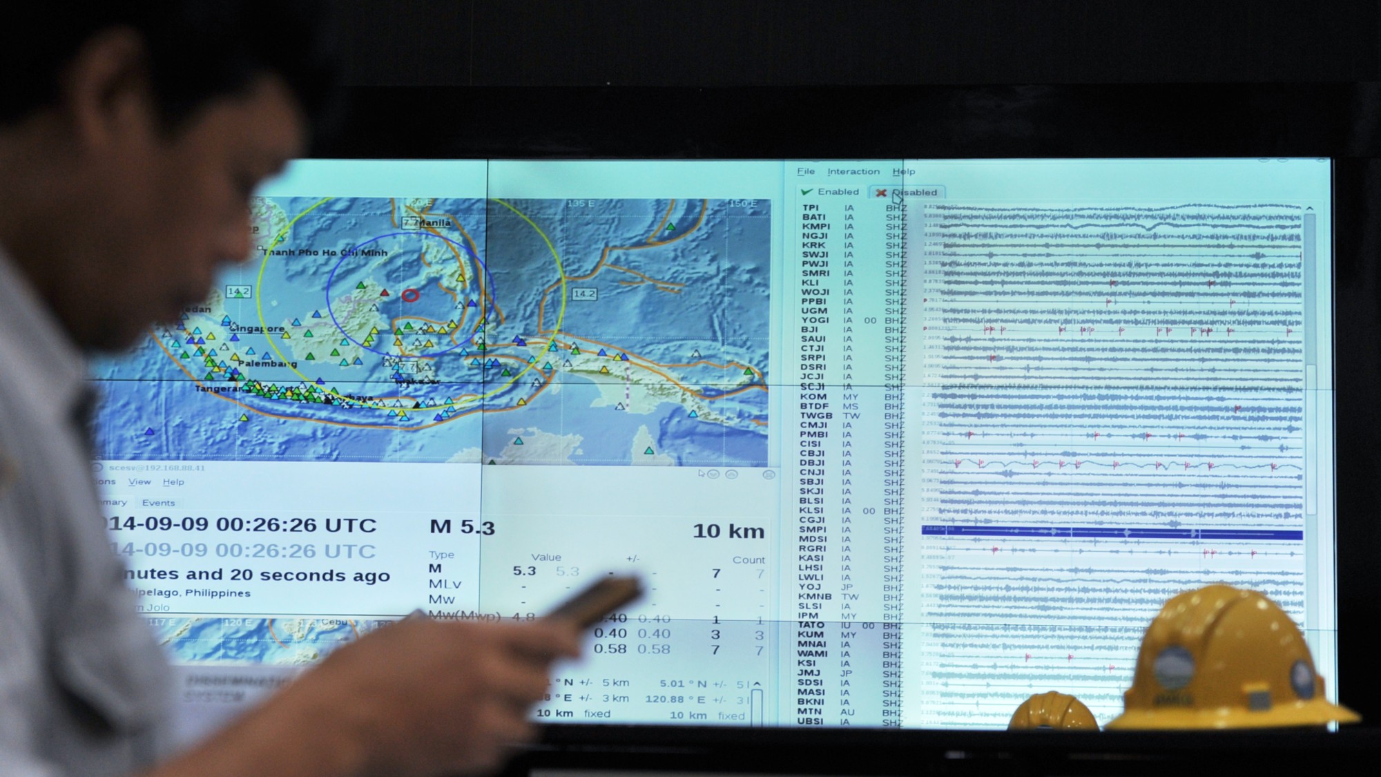 An Indonesian official checks his smartphone for an earthquake alert on Sept. 9, 2014. 