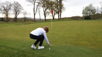 Brushing sand away from the fringe of the green