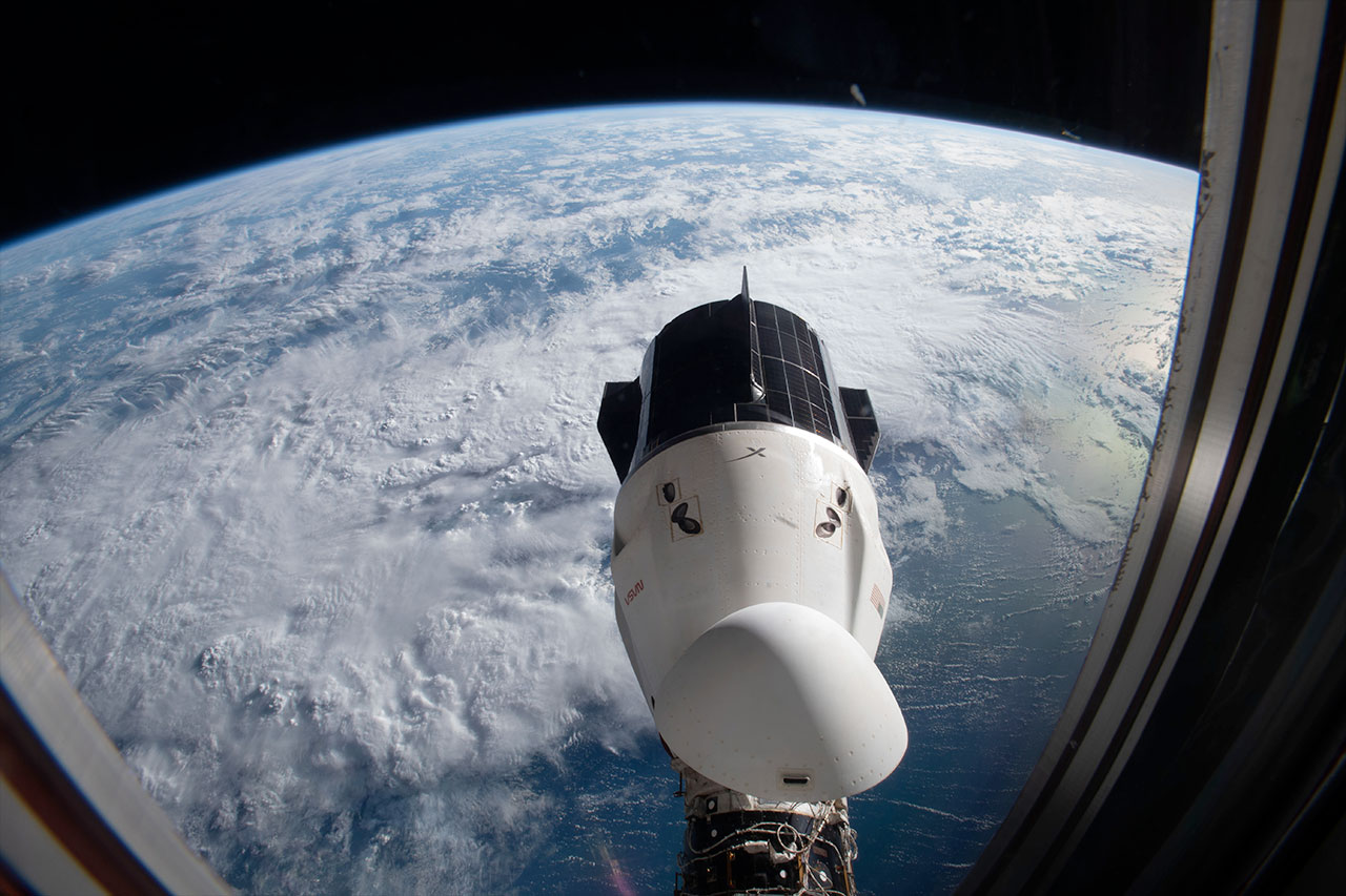 a spacex crew dragon docked to the international space station with earth in behind