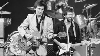 George Harrison (1943 - 2001, left) and Eric Clapton at Limehouse Studios in London during recording of the TV programme 'Blue Suede Shoes', spotlighting veteran rockabilly songwriter and guitarist Carl Perkins. In the background are drummers Slim Jim Phantom and Ringo Starr.