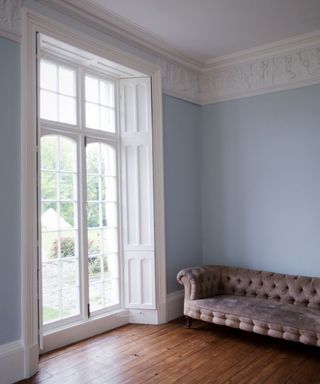 period room with large glass doors, wooden floor and pale blue walls