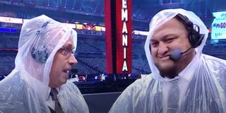 Michael Cole and Samoa Joe with rain ponchos on during commentary for WrestleMania 37.