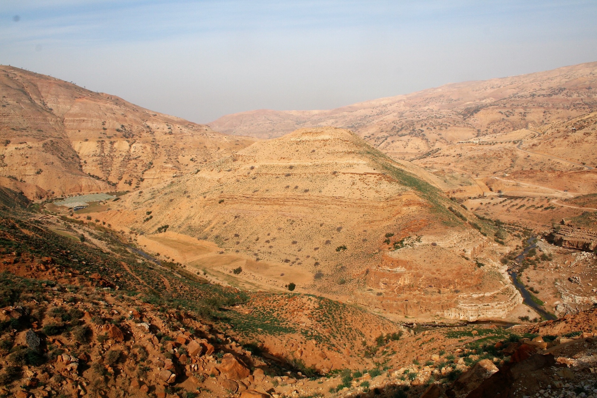 an aerial view of a hilly desert landscape with some greenery