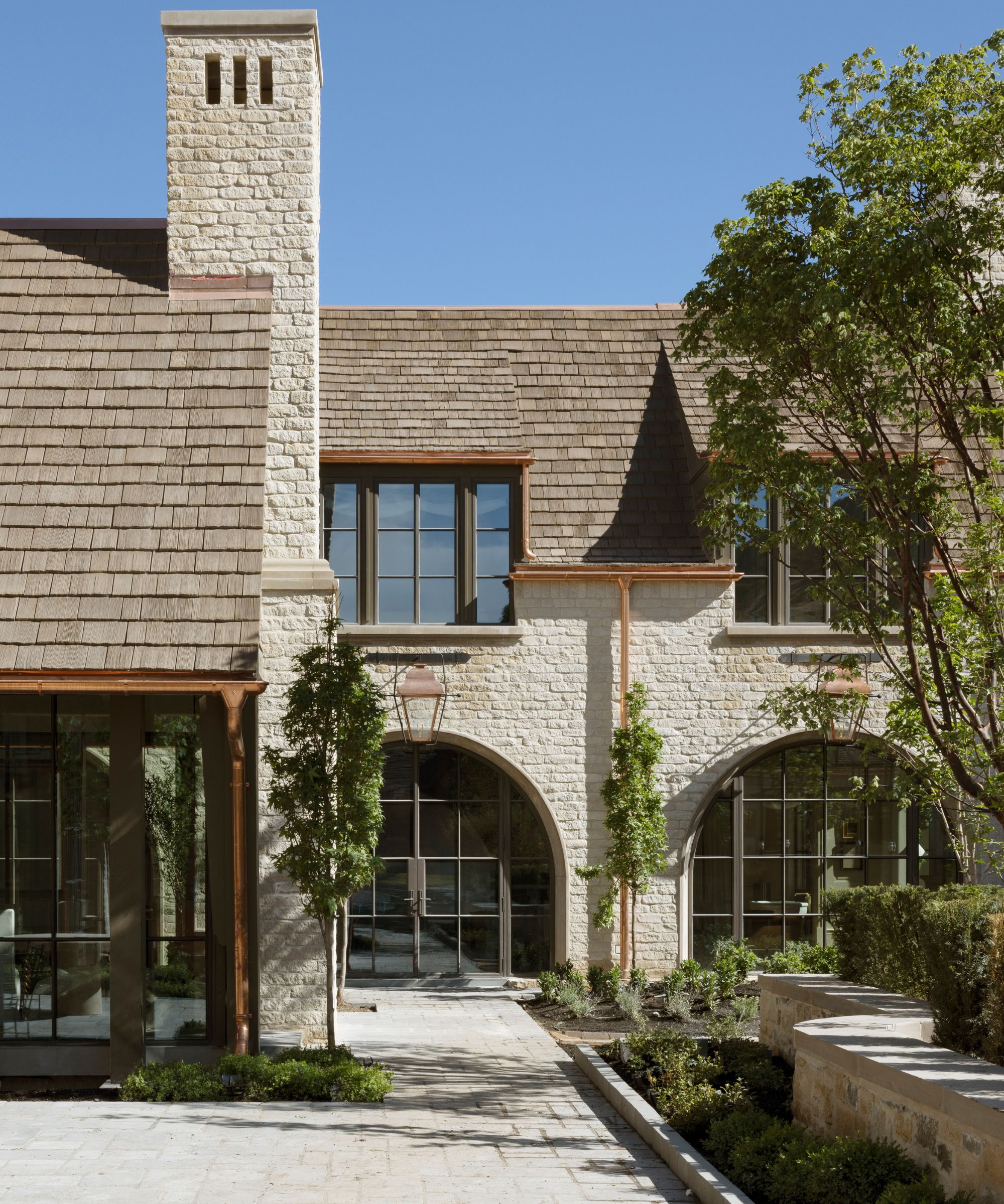 a large utah new build home with light stone brick facade, large chimney and tailored landscaping