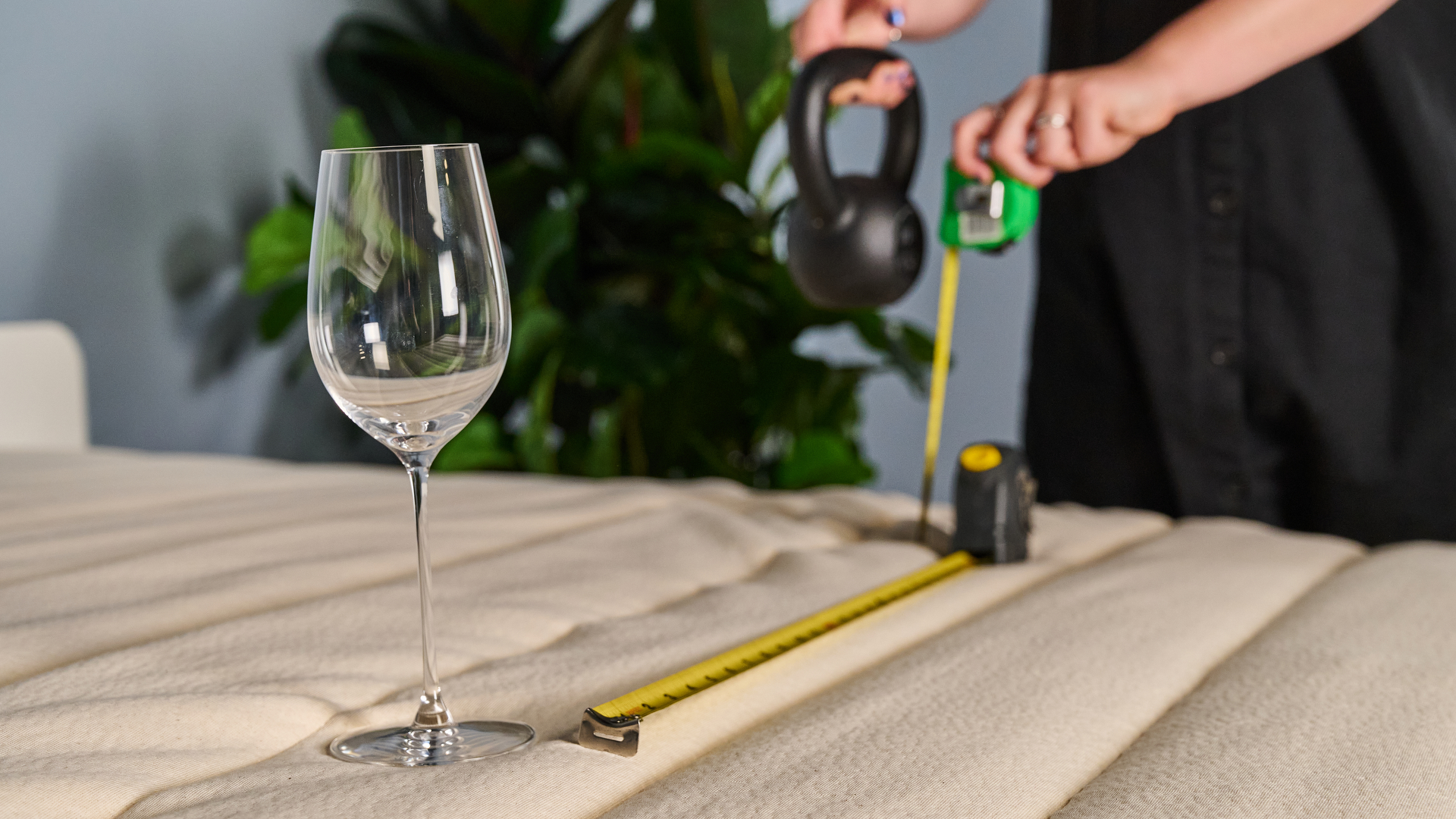 A Tom's Guide tester holding a weight away from a wine glass to measure the motion isolation