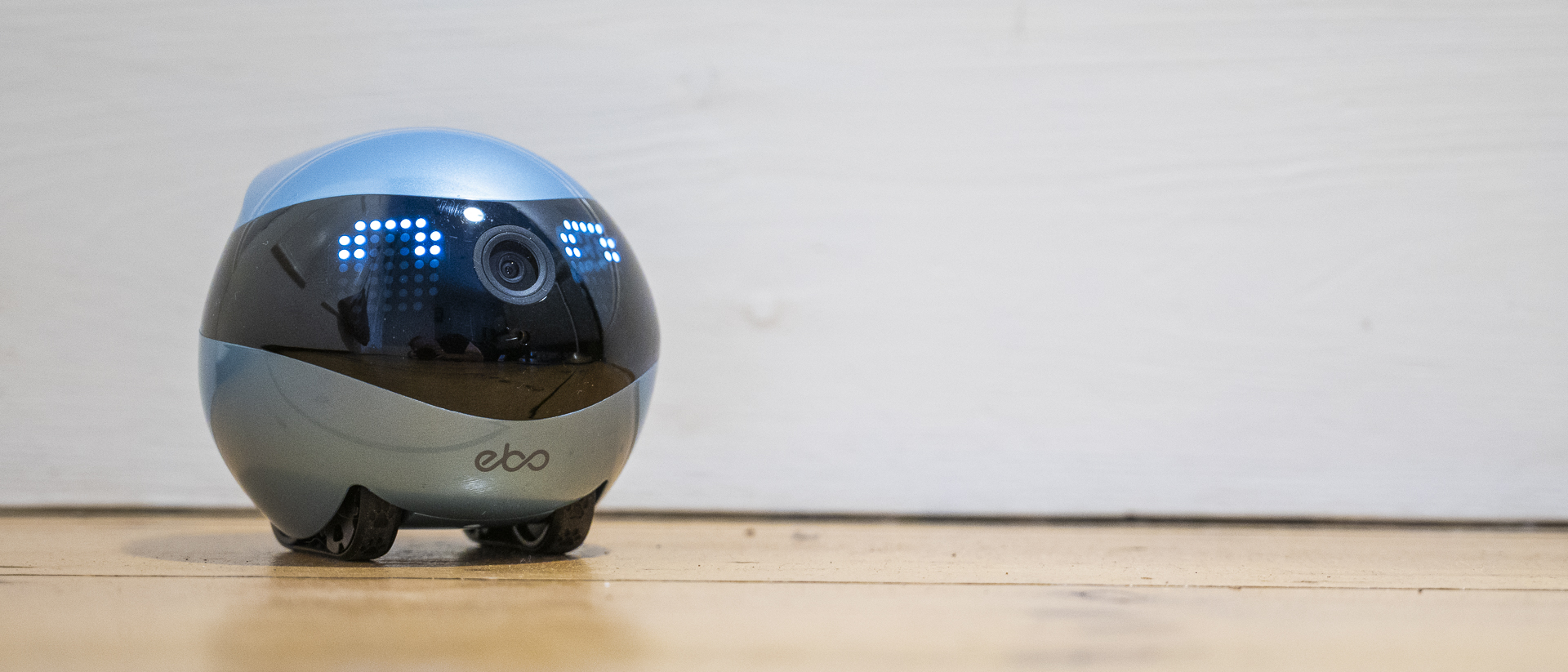 Enabot Ebo Air 2 on a wooden floor with a white skirting board behind