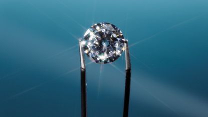 A pair of tweezers holding a diamond