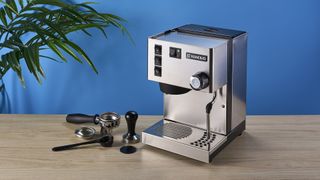 Rancilio Silvia in Stainless steel on a wooden worktop with a blue wall in the background.