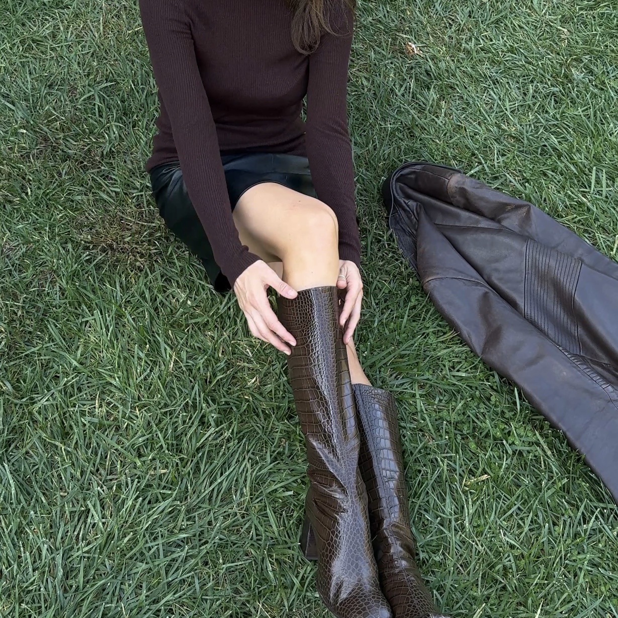 Kathryn Zahorak wearing brown turtleneck, leather skirt, and knee high boots