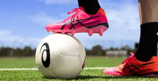 Pink Asics football boot on a football
