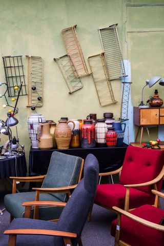 A flea market features colorful mid-century modern sofas in blue, black, and red, as well as plenty of ceramics, lamps, and cabinets.