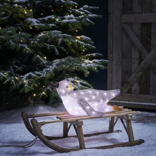 light up bird sitting on a sleigh with a Christmas tree and snow