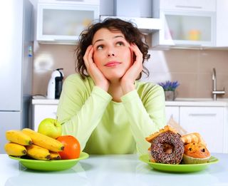 A woman thinks about whether to eat fruit, or donuts.