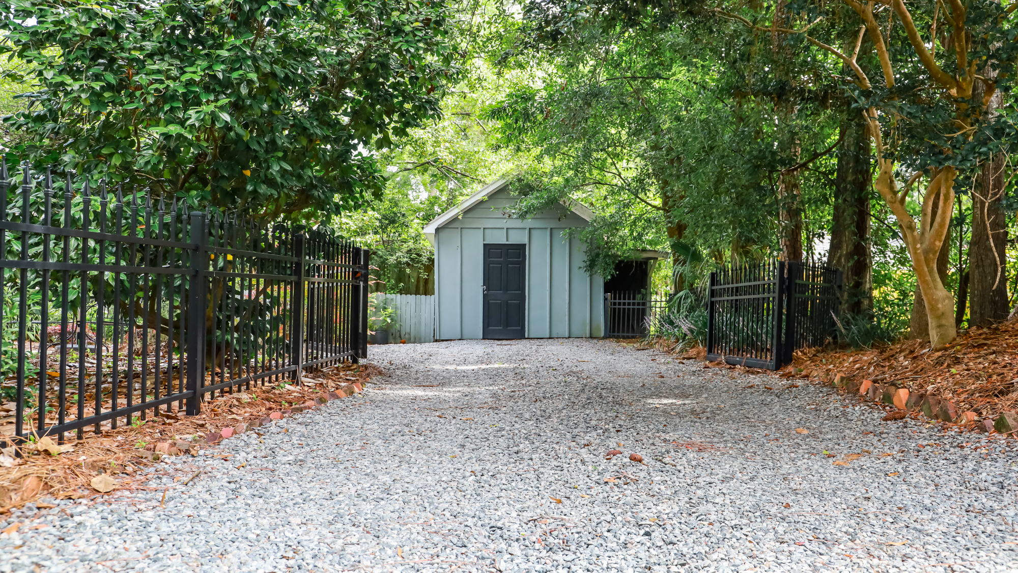 gravel driveway with fence and shed 