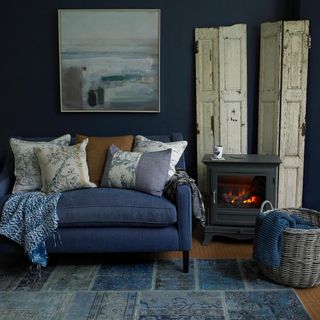 living area with painting and blue wall and blue sofa with cushions and fireplace
