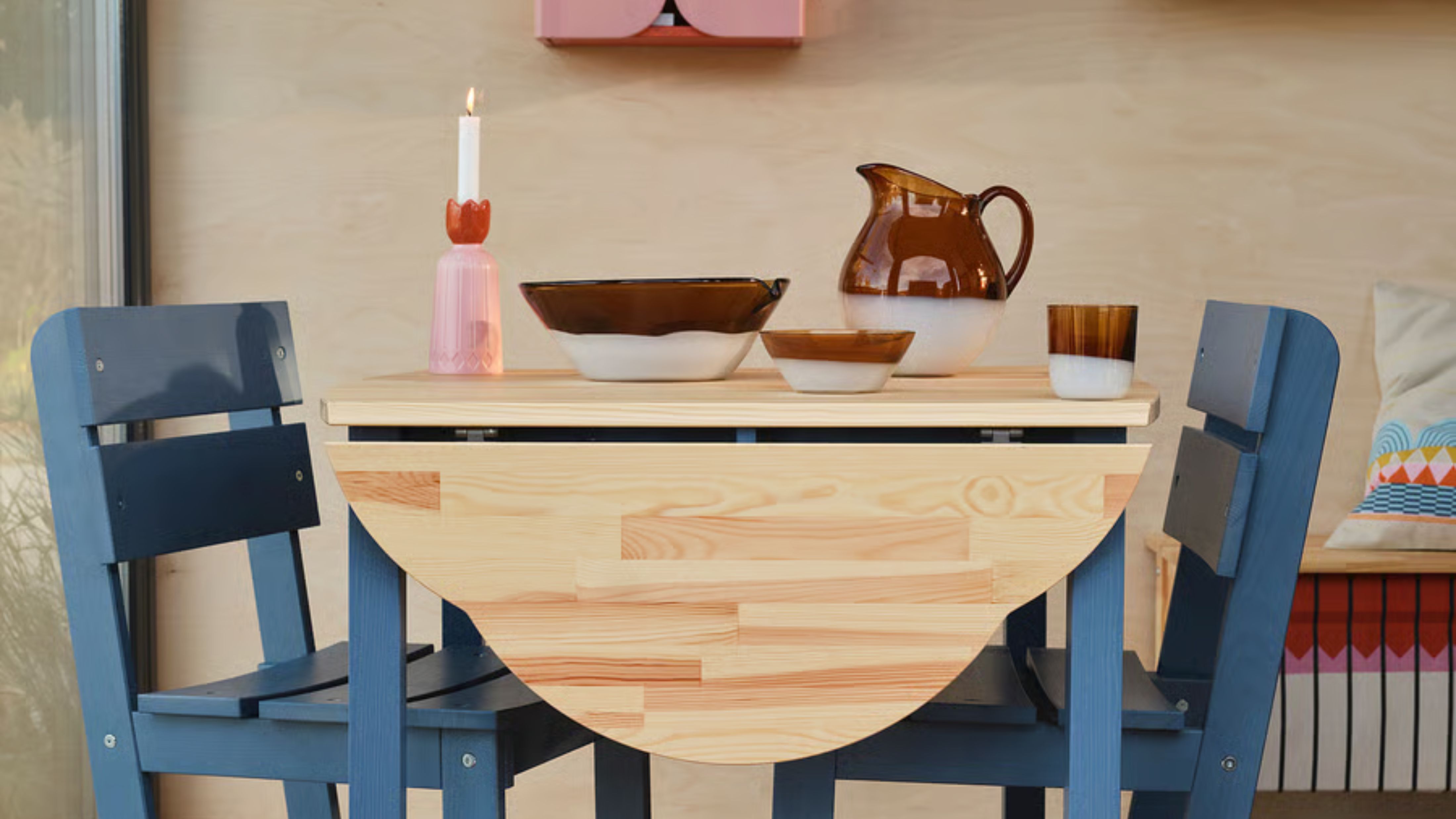 Breakfast table vignette featuring a wooden folded-leaf tabletop, blue chairs, and eclectic table decor 