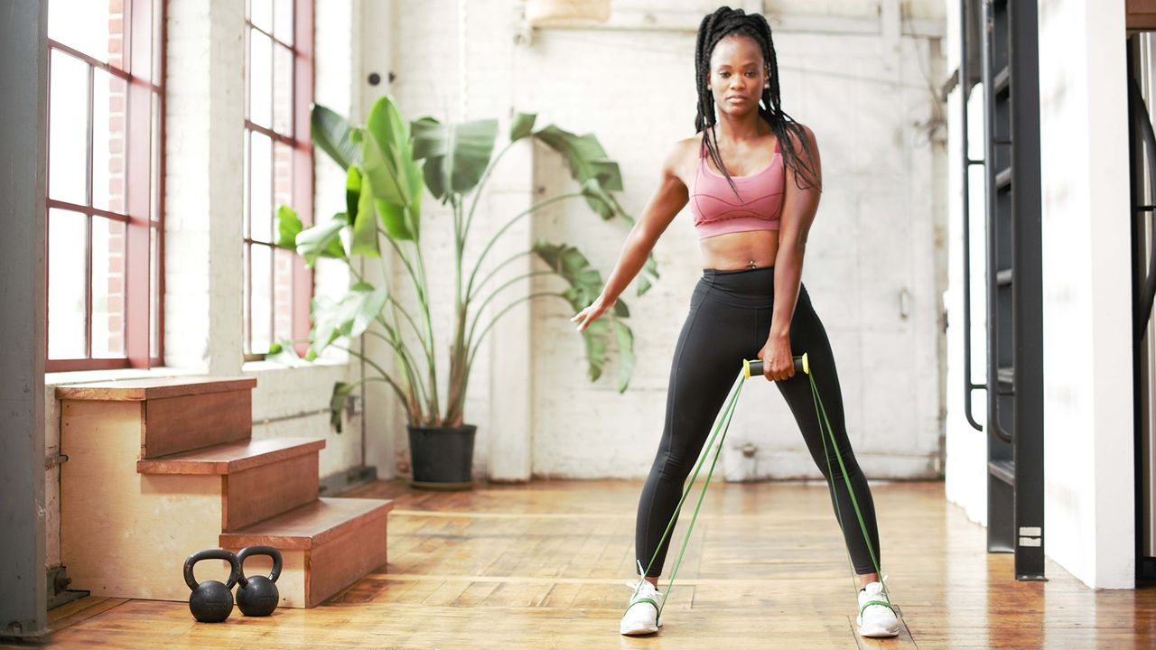 Fit young woman using resistance band with the TRX Bandit handle