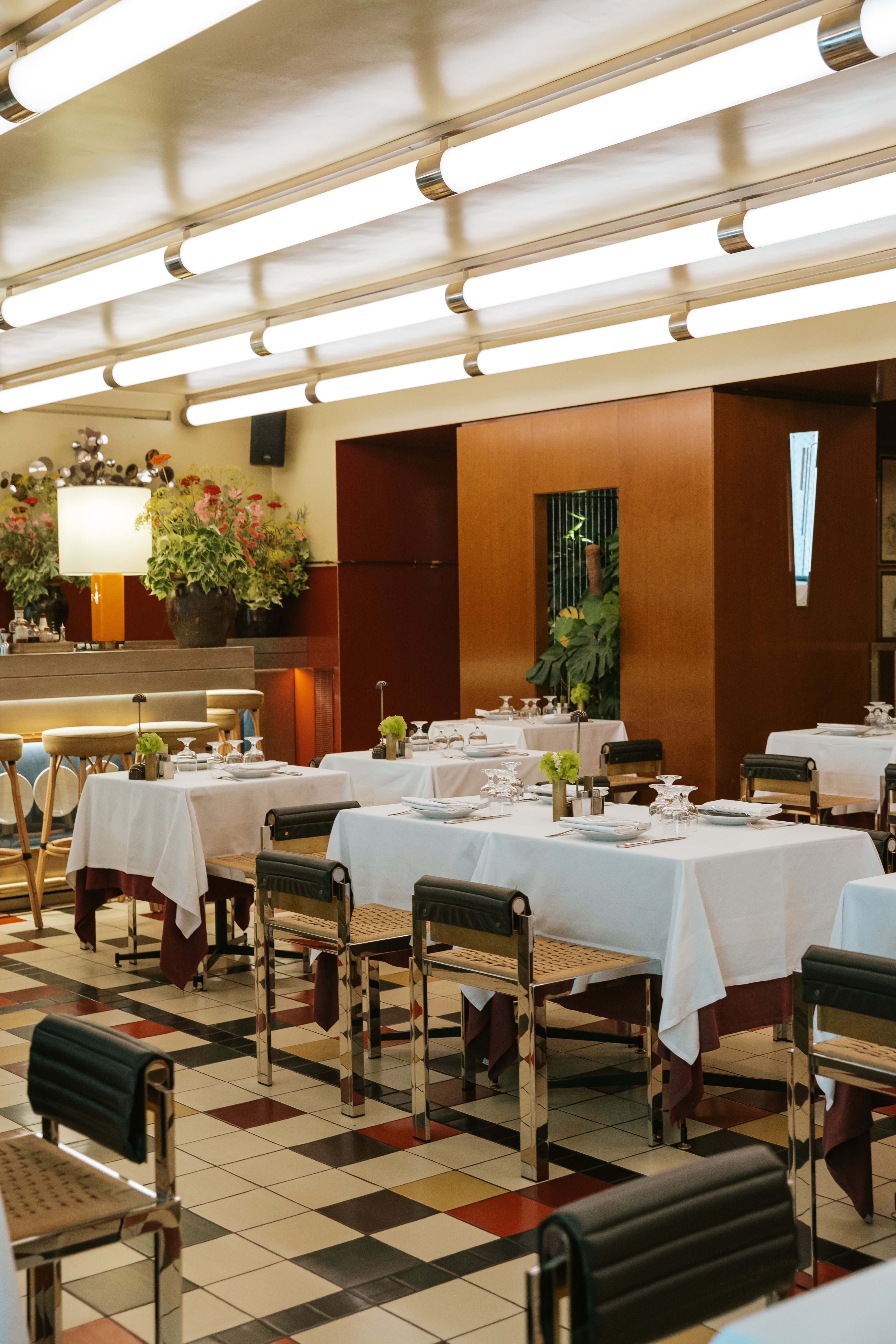 A retro-inspired restaurant&#039;s ambiance features coffered ceilings, a red, black, cream, and ochre palette, and mid-century leather, rattan, and chrome chairs, while simply delicious, vegetable-based plates reproduce the same colors.