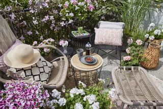 tiny gravel patio area with pink flower and garden seating
