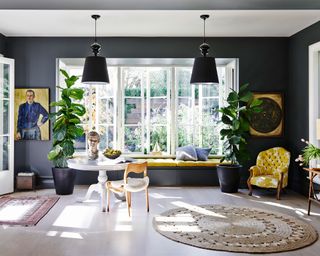 A black living room with pendant lighting, a yellow window seat and yellow armchair.
