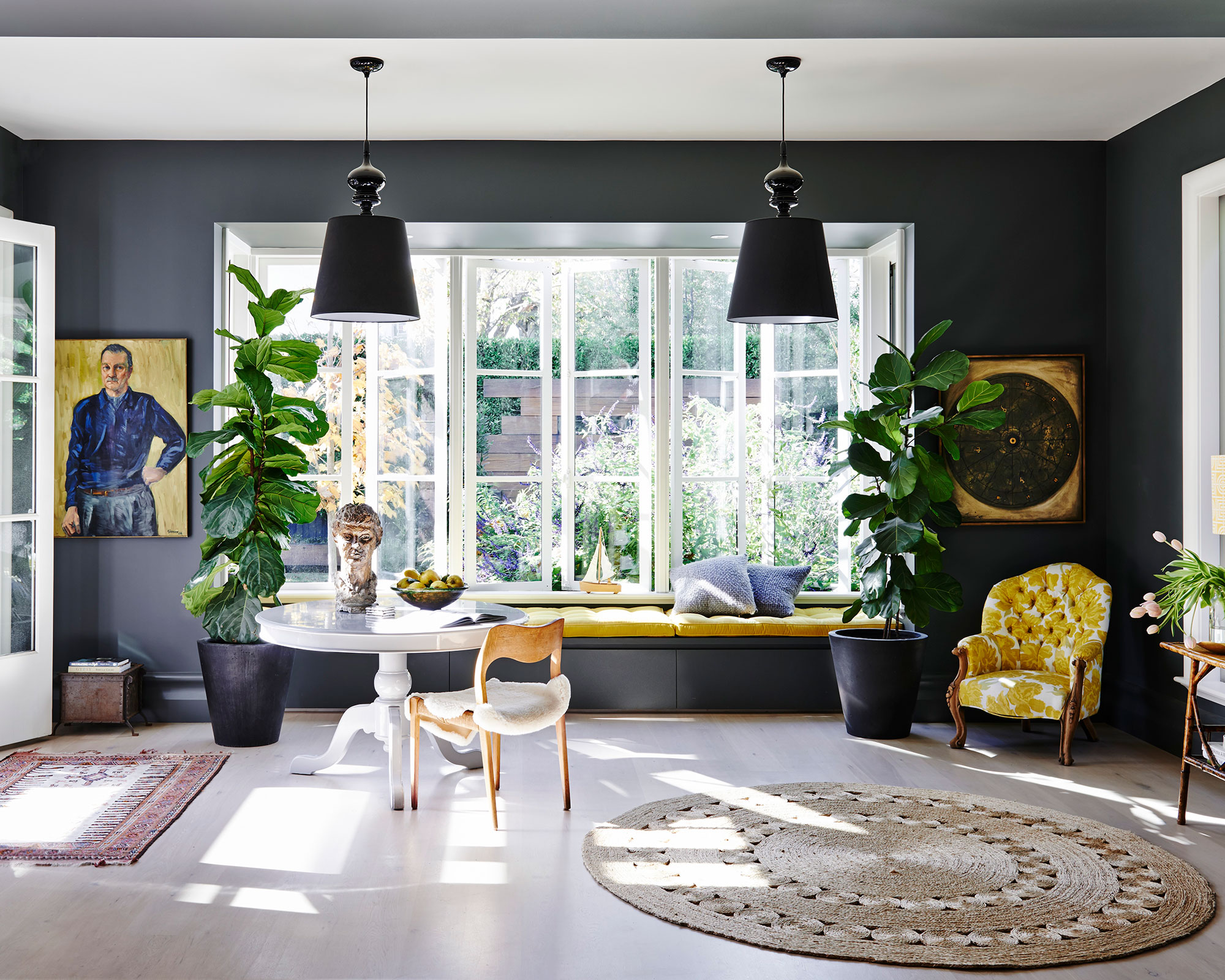 A dark living room with a large window, dark grey walls and yellow furniture