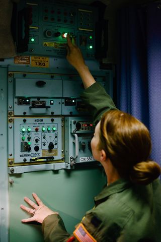 Captain Amber Moore adjusts one of the capsule's myriad communications systems, all of which—with their floppy disks and landlines—are from another era.