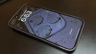 En Apple iPhone 14 Pro Max ligger på en mörk yta och visar upp sin always-on-skärm.