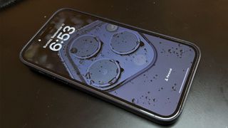 Apple iPhone 14 Pro Max ligger på et bord med skærmen tændt