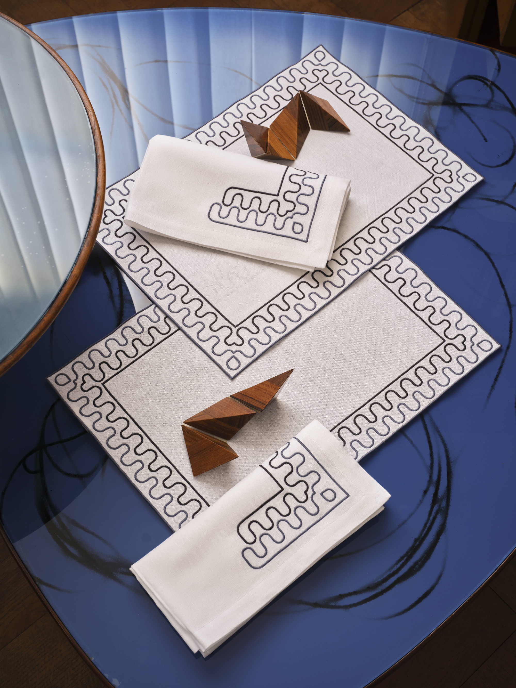 A royal blue table with white table cloths that have a blue wavy border on them.