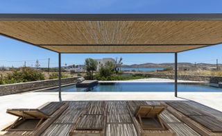 Swimming pool and deck chairs under blue skies in KITE House in Greece