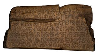 A wooden tablet with glyphs carved onto it.