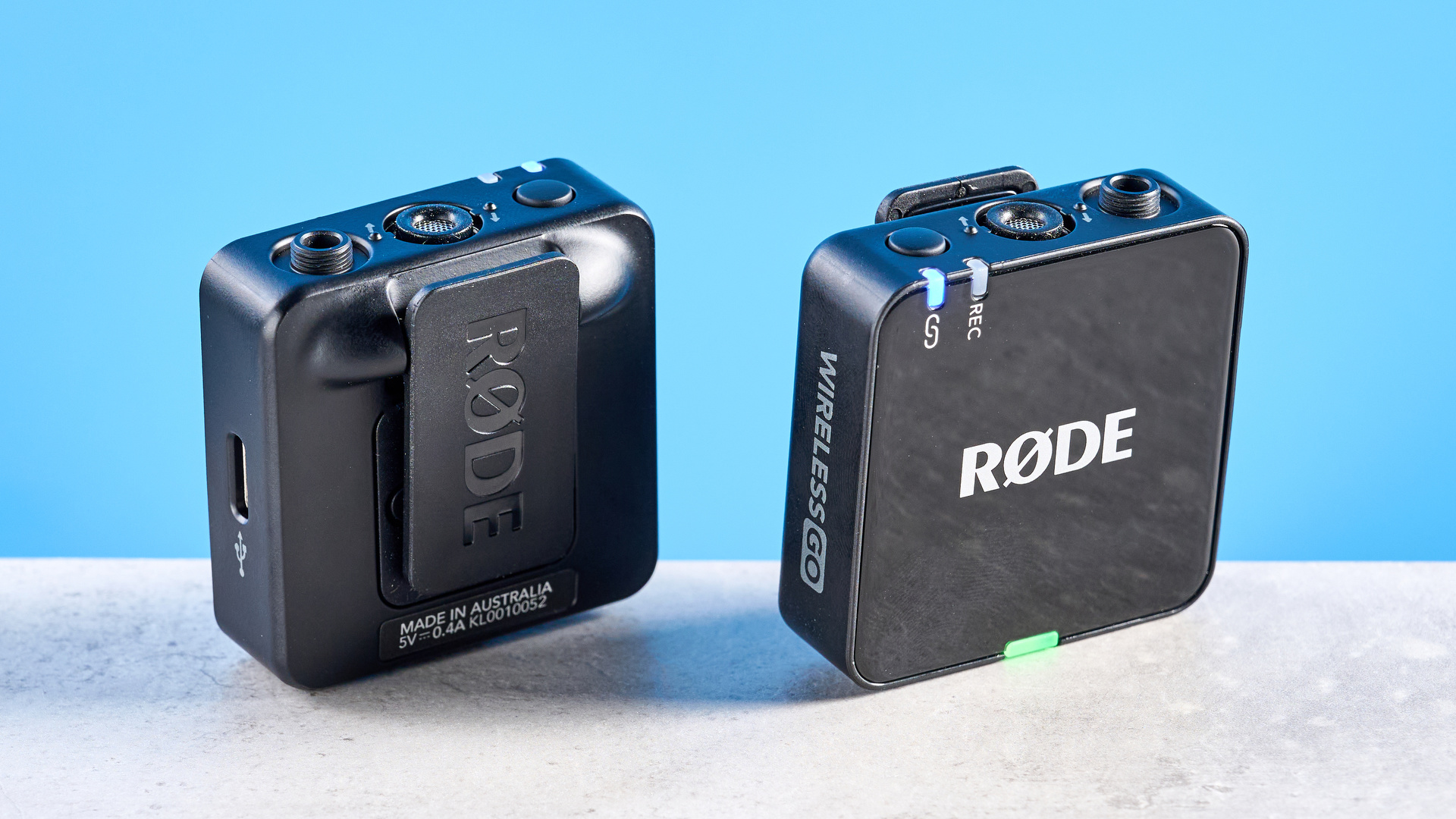 the rode wireless go gen 3 microphone with one receiver, two transmitters, shown against a blue background and with accessories like dead cat, charging ports, and cables