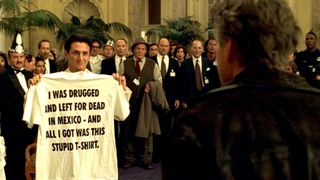 Sean Penn as Conrad "Connie" Van Orton holding up a shirt in the middle of a crowded room in the movie The Game
