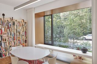 Dining area and library shelving looking out towards greenery in Toronto suburban house