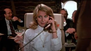 Teri Garr takes a phone call enthusiastically with a glass of champagne in hand in Mr. Mom.